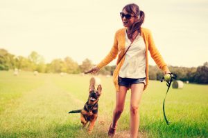 Women enjoy with her dog. They running on field together